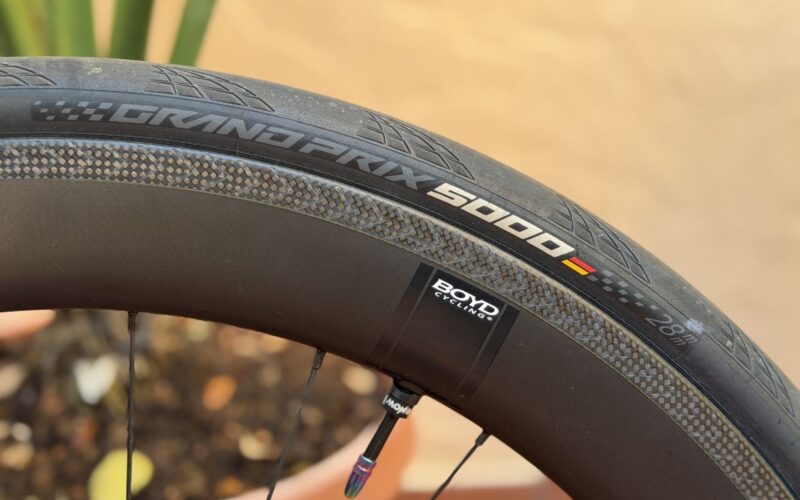 Close-up of Continental Grand Prix 5000 clincher tire mounted on a carbon road wheel, showing sidewall branding and tread pattern